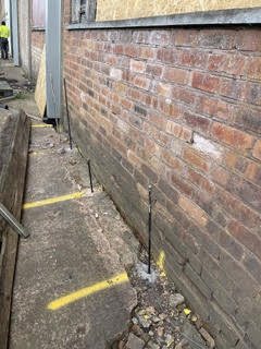 Resin injection lances beside a brick foundation